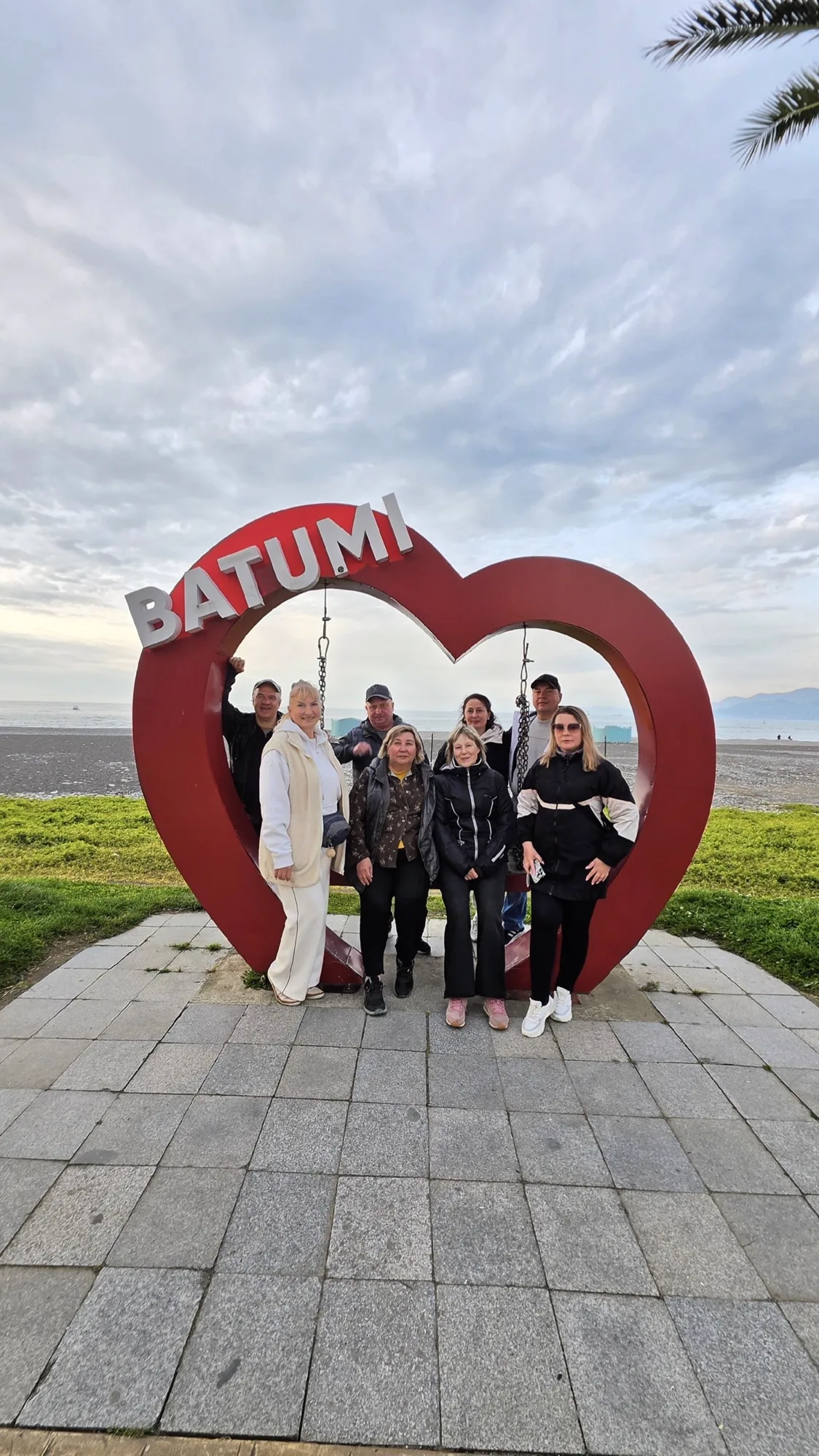 Группа туристов у арки-сердца с надписью Batumi на набережной